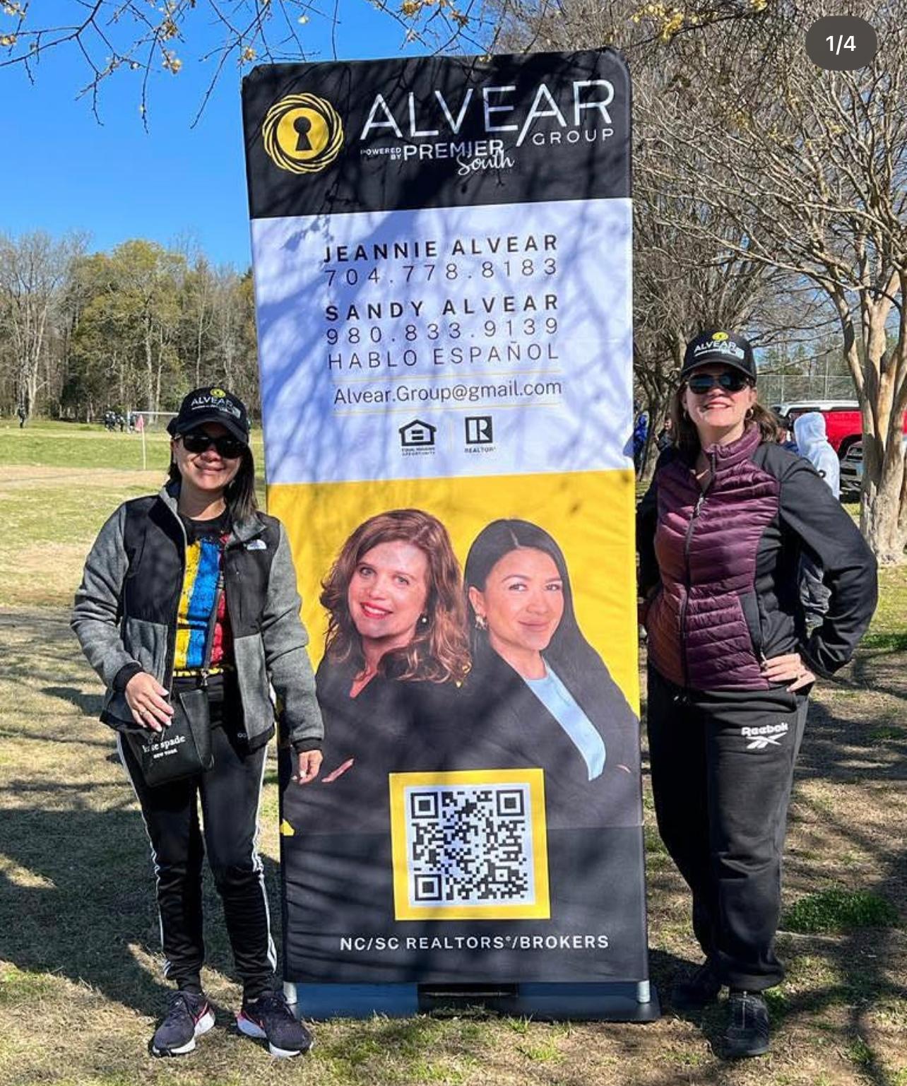 Jeannie and Sandy Alvear at outdoor NC community event with banner