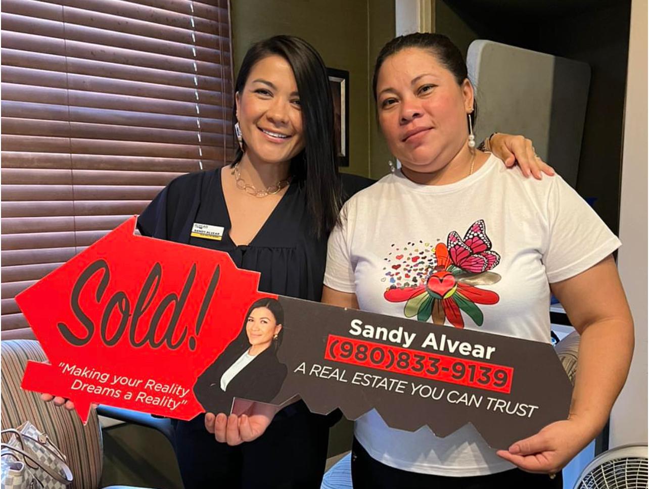Sandy Alvear with client at interior closing with sold sign